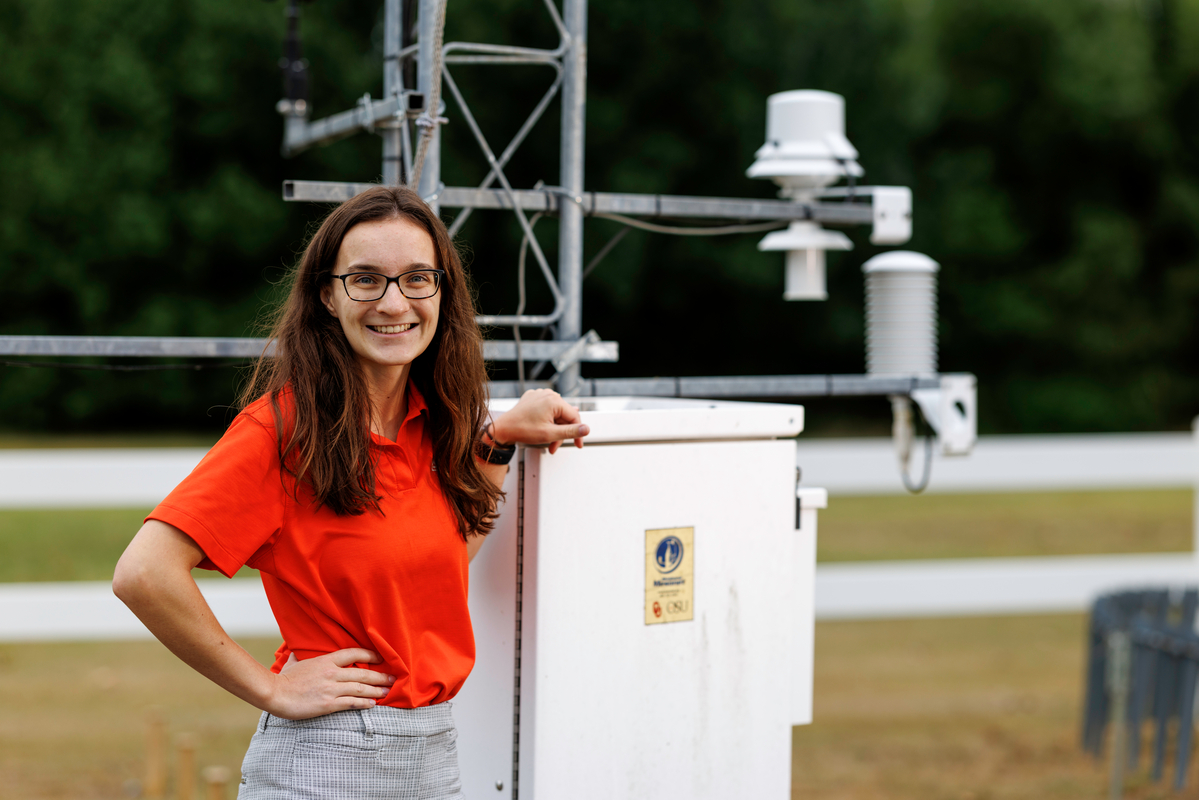 Emma White stands in front of a Mesonet site