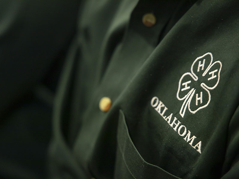 green button-up, collared shirt with the 4-H logo on it