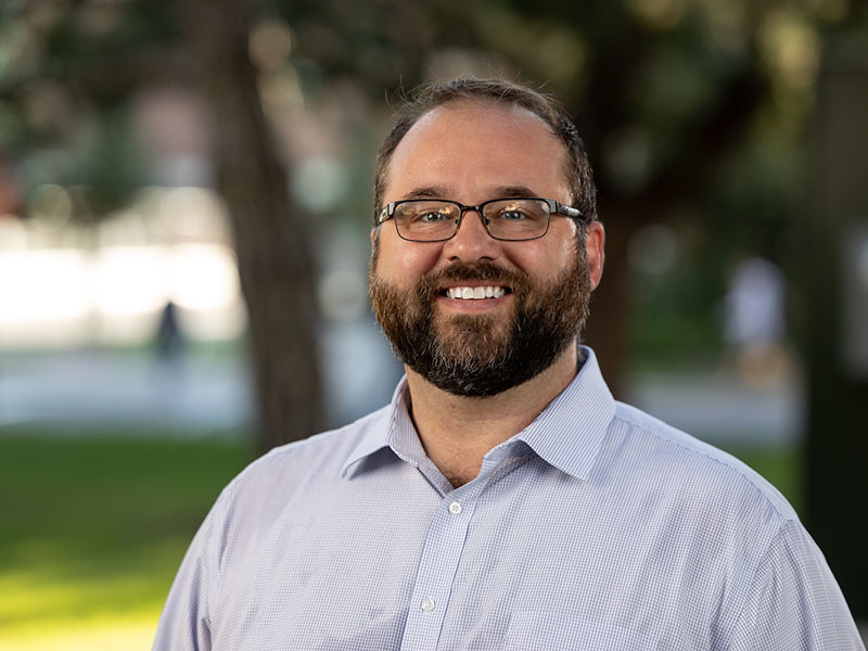 Tyler Mason, a man with brown hair, glasses and a light blue, collared, button-down shirt