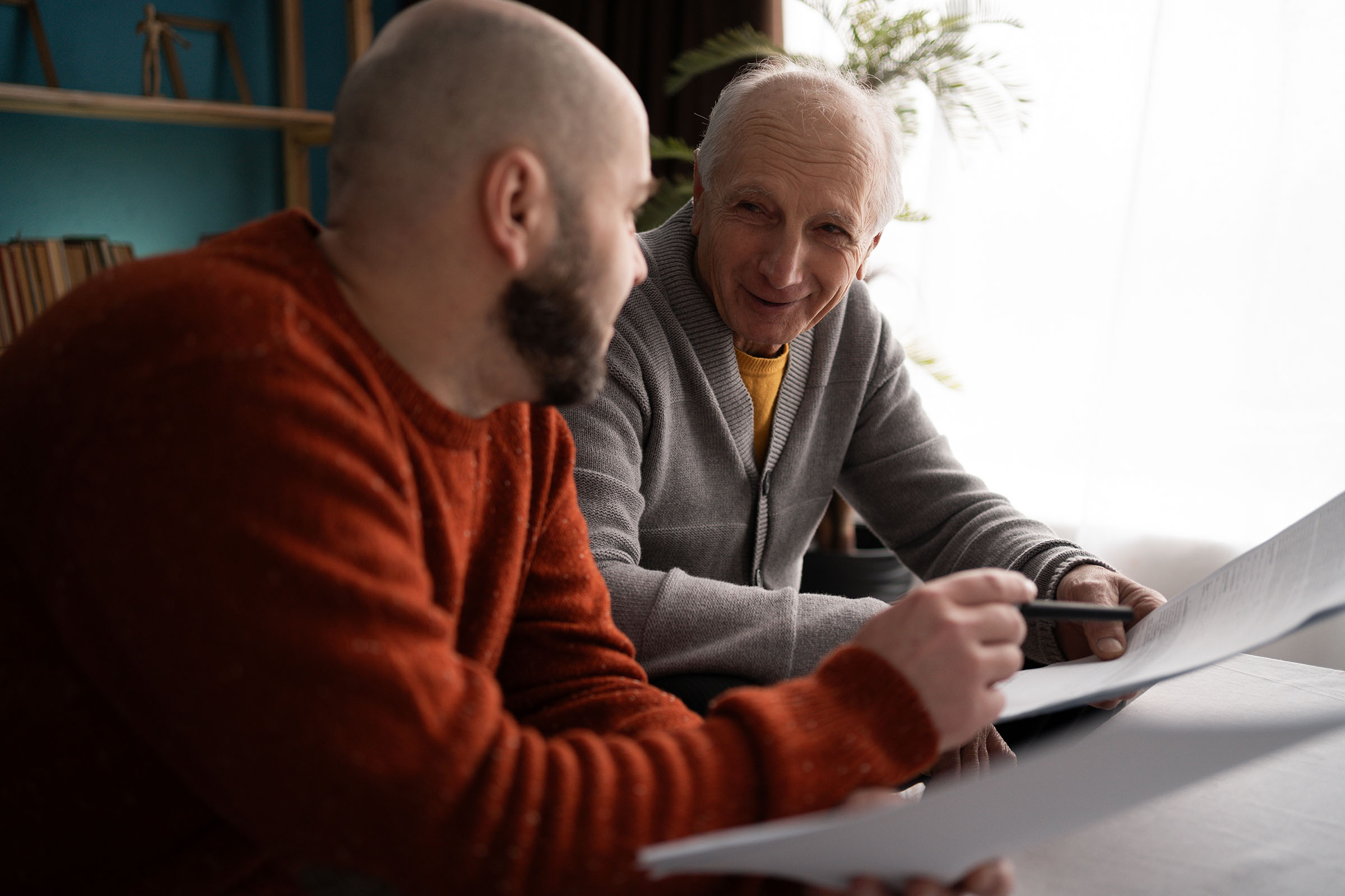 Two people sitting at a table reading some papers.