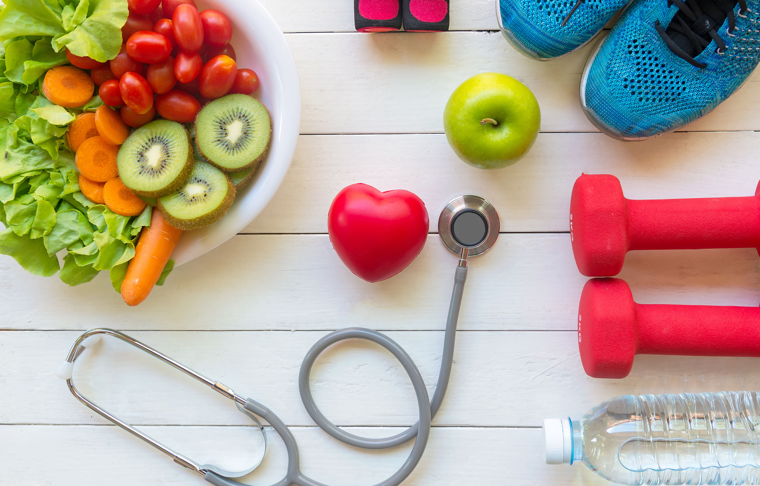 March FCS 2026 National Nutrition Month Top view of fresh fruits and vegetables, a green apple, dumbbells, running shoes, water bottle, stethoscope and red heart on a white wooden surface.