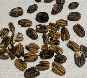 A cluster of pecans on a table that have black spots across several of them.