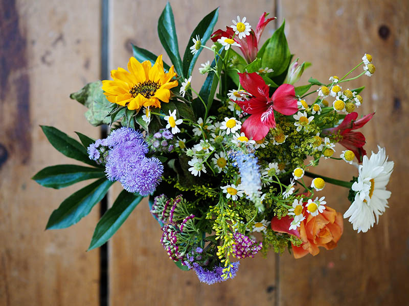 Floral arrangement with many colors with a wood background.