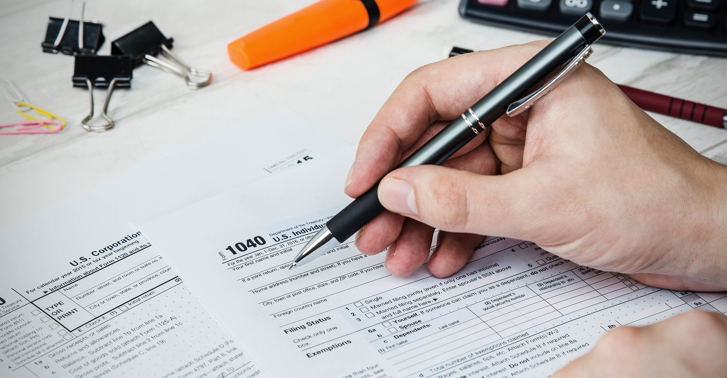 A person's hand filling out tax documents.