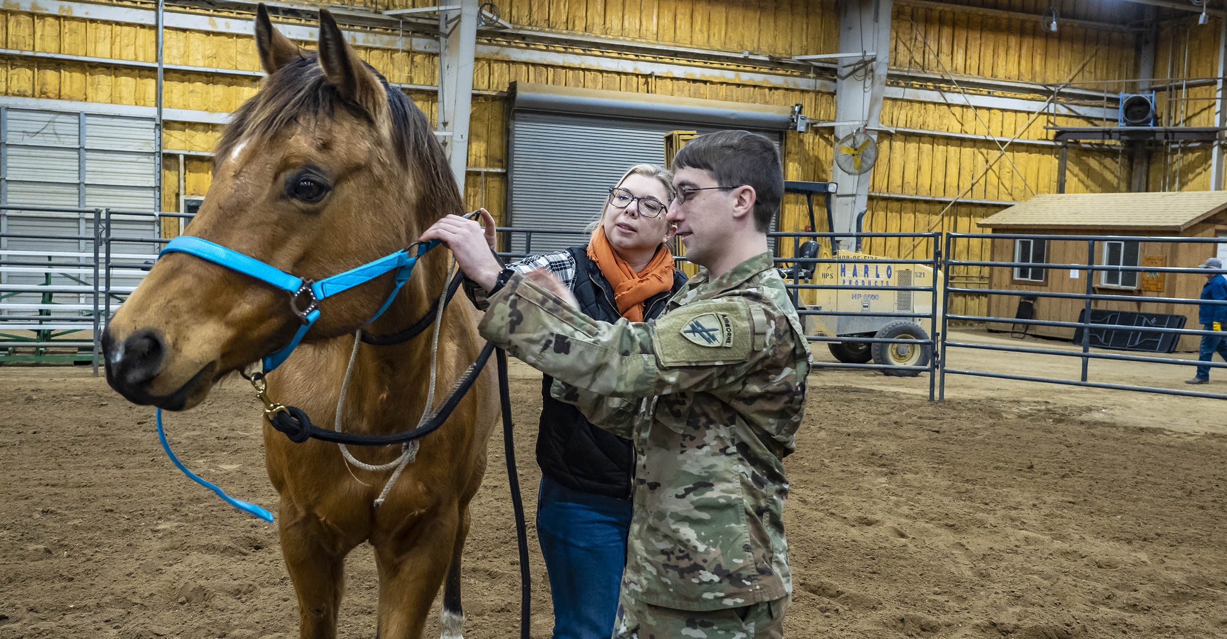 Amy Hagerman, OSU Extension specialist for agriculture and food policy, demonstrating how to halter a horse to an Oklahoma Army Reserve soldier in a barn.