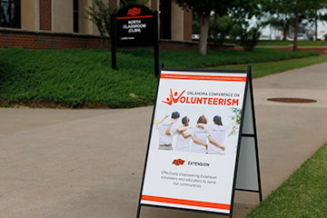An Oklahoma Conference on Volunteerism sign stands outside the North Classroom building on the OSU campus in Stillwater.