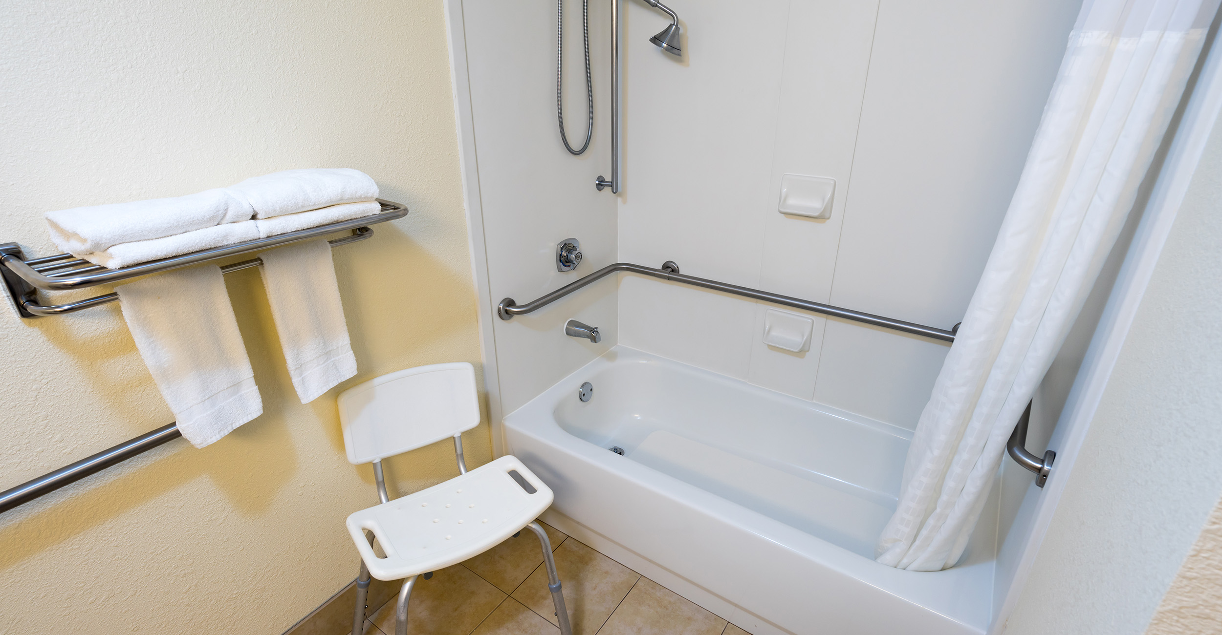Bathroom with a shower seat and grab bars.