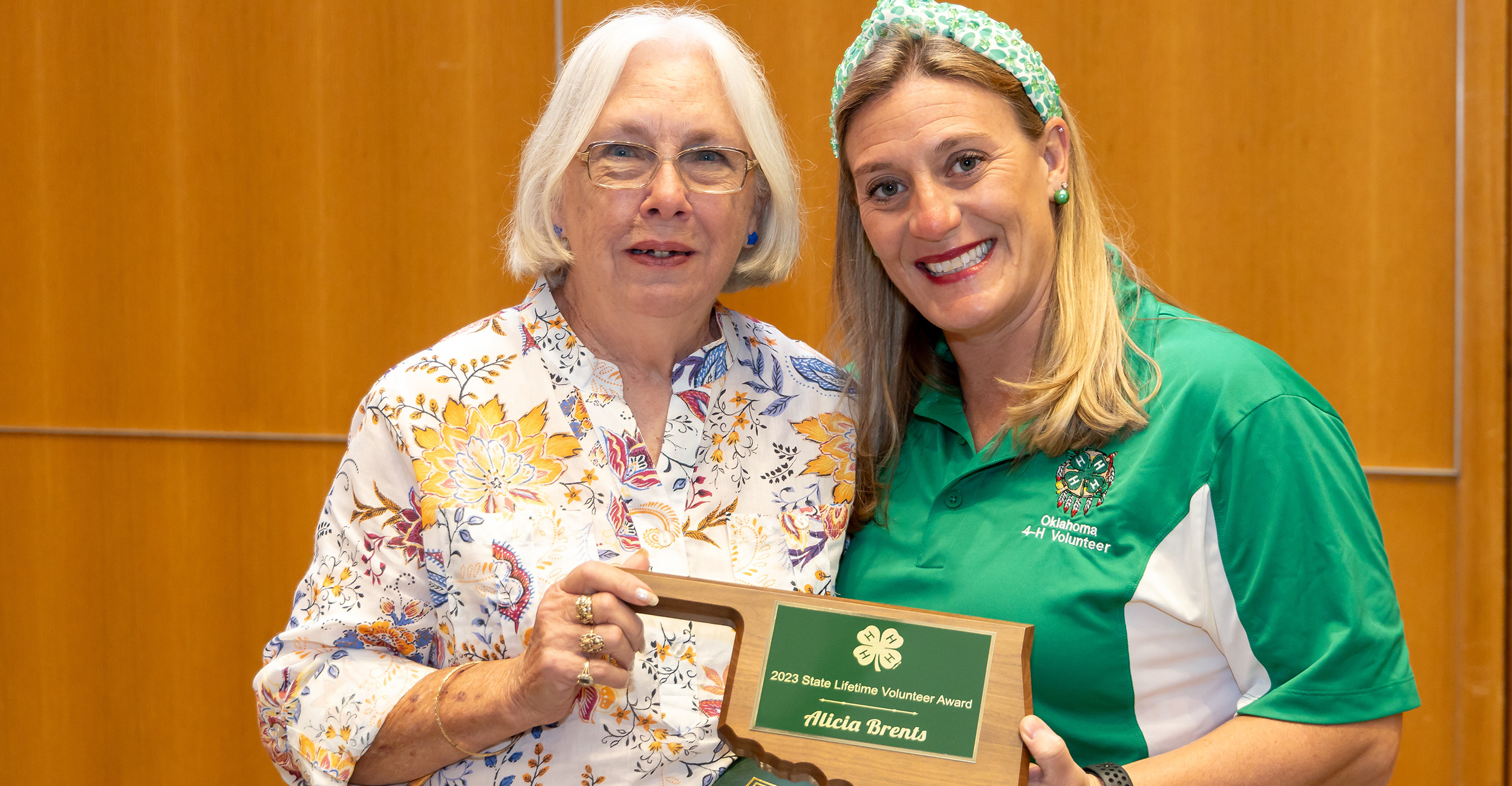 Two women holding a plaque and certificate.