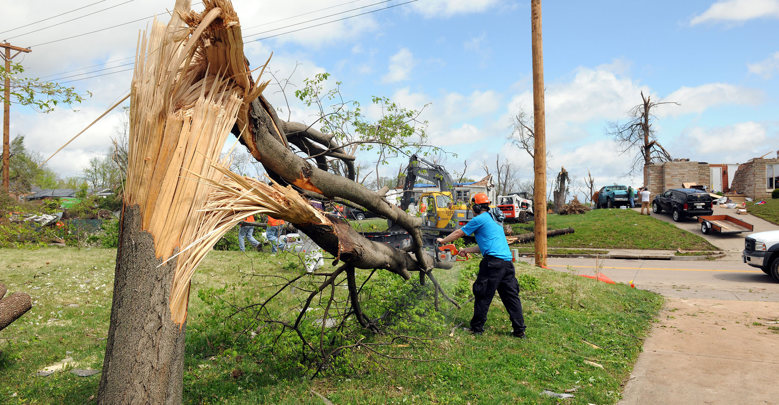 Person cutting a storm-damaged tree with a chainsaw.
