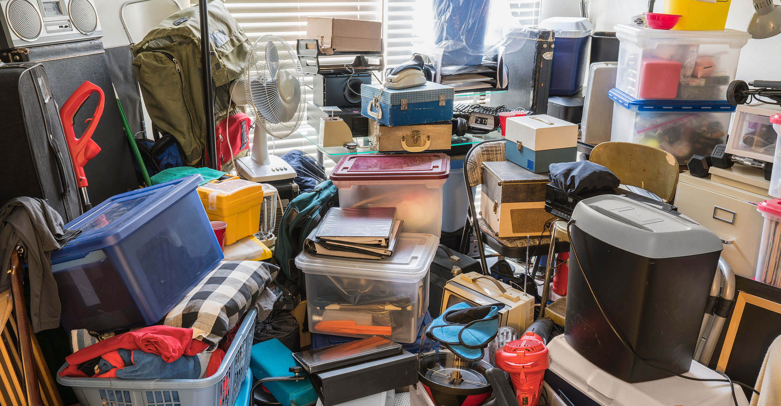A room in a home piled with clutter, boxes, notebooks and other items that make the space unusable and cause a safety hazard.