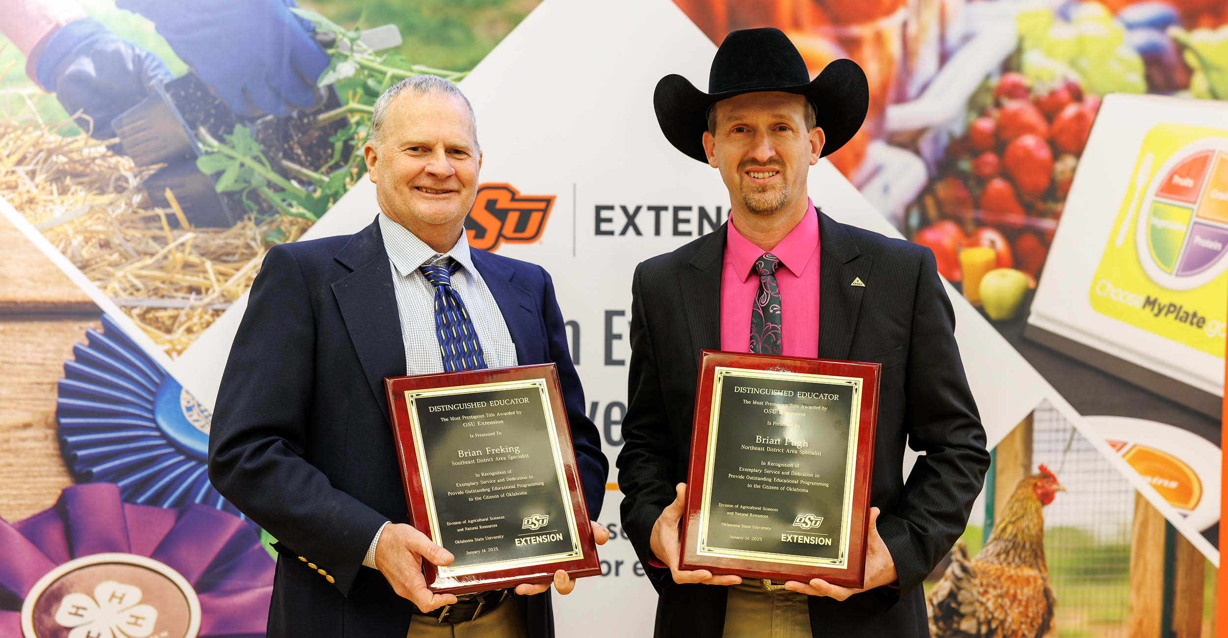 Brian Freking on the left holds his award plaque wearing a blue and yellow tie, khaki pants, blue suit coat and white shirt. Brian Pugh on the right holds his plaque wearing a pink and black tie, pink shirt, black suit coat, black cowboy hat and khaki pants.