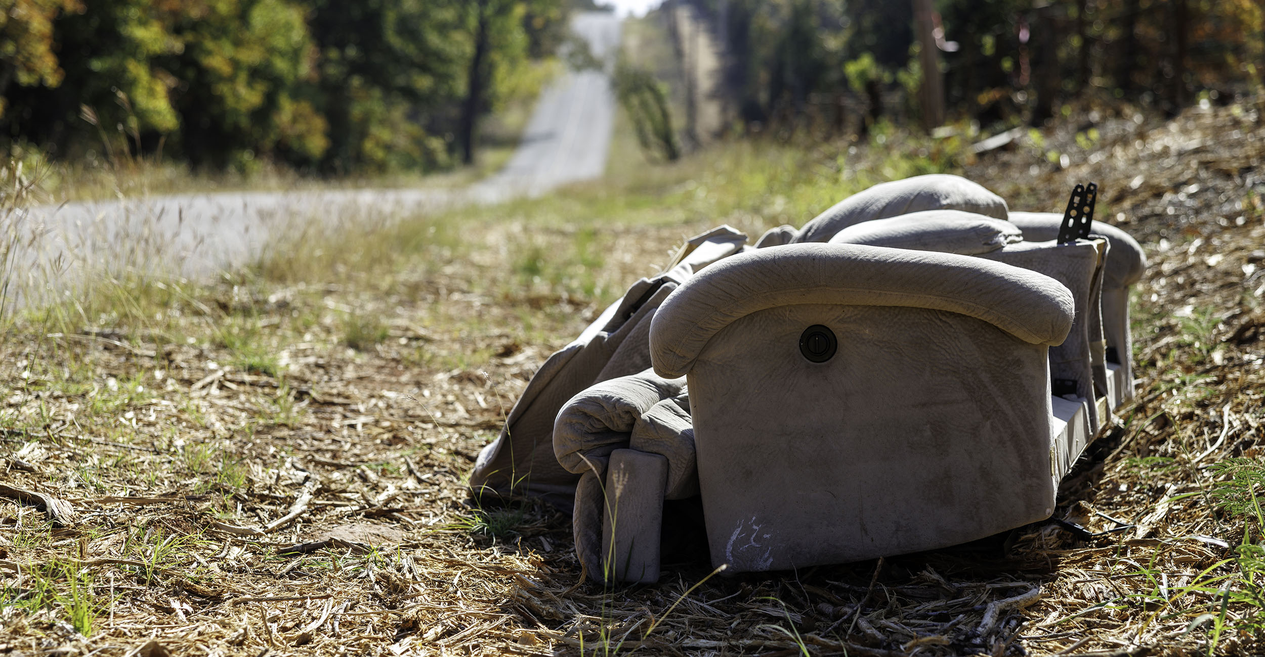 An old couch has been illegally dumped alongside a highway.