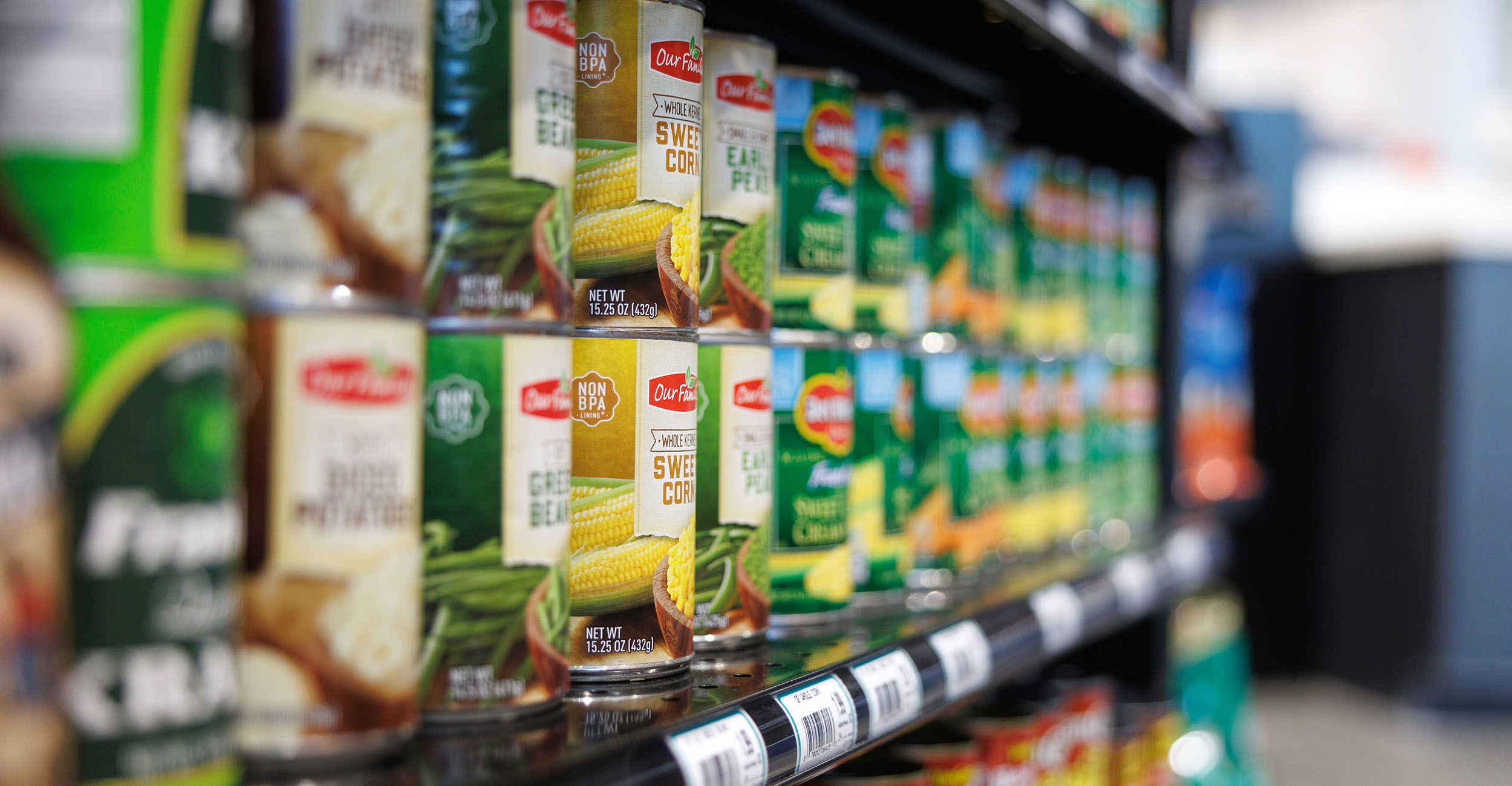 Grocery store shelf filled with canned foods.