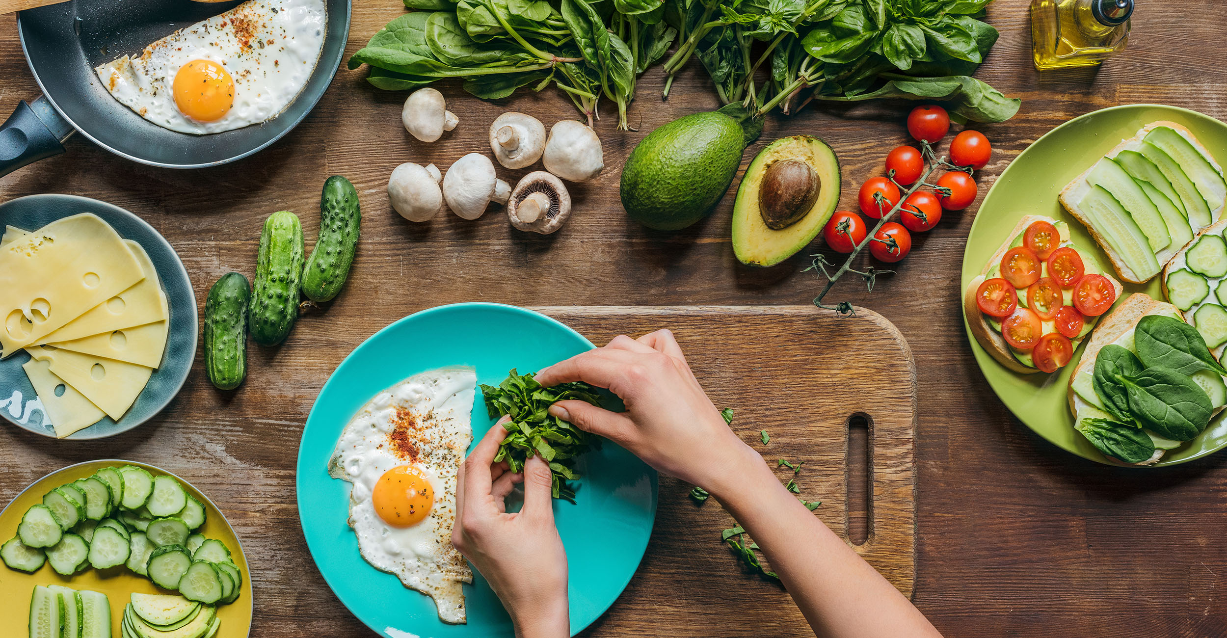 A woman's hands place healthy fruits, vegetables and proteins on a blue plate.