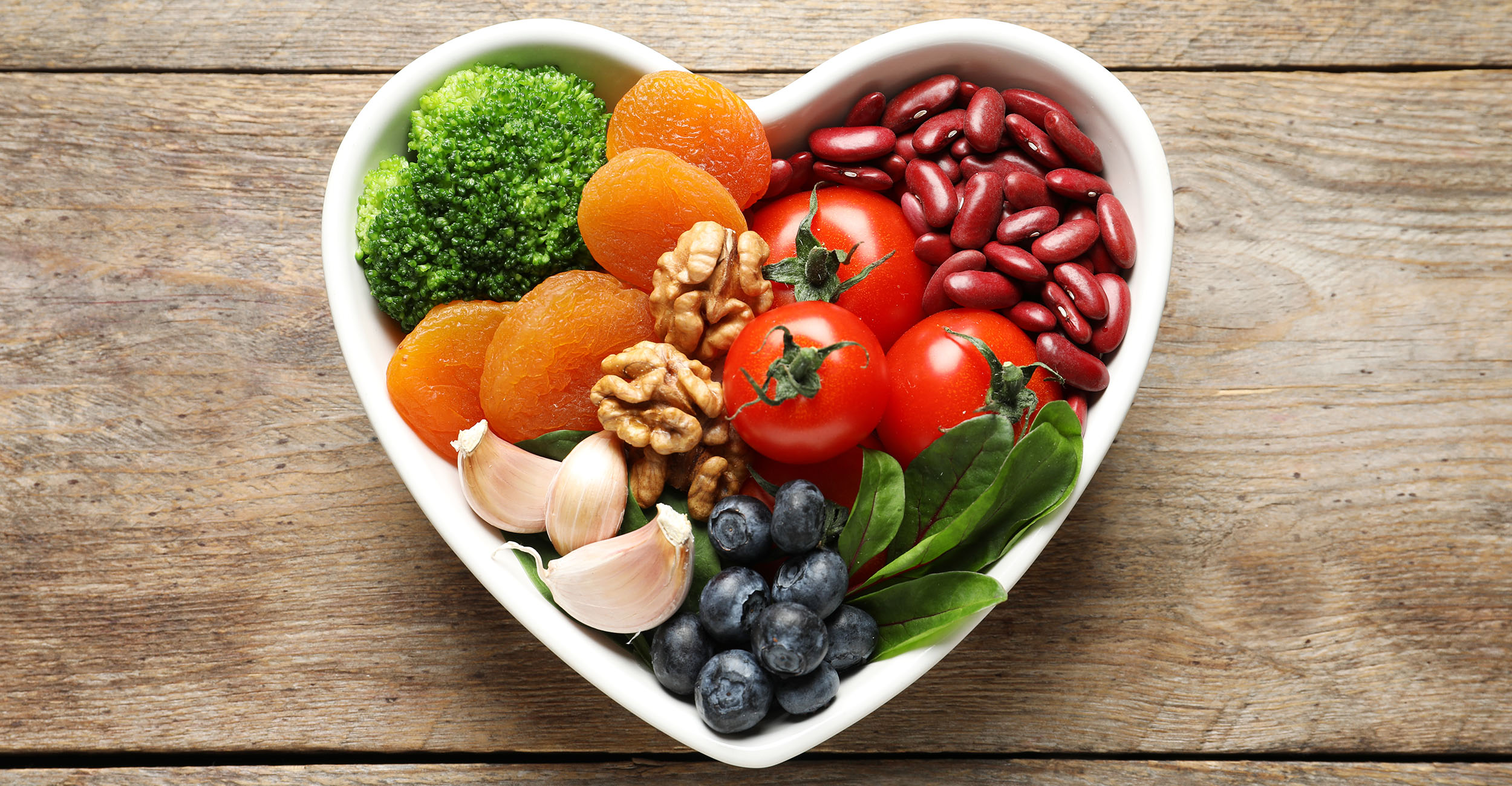 Heart-shaped bowl filled with healthy foods.