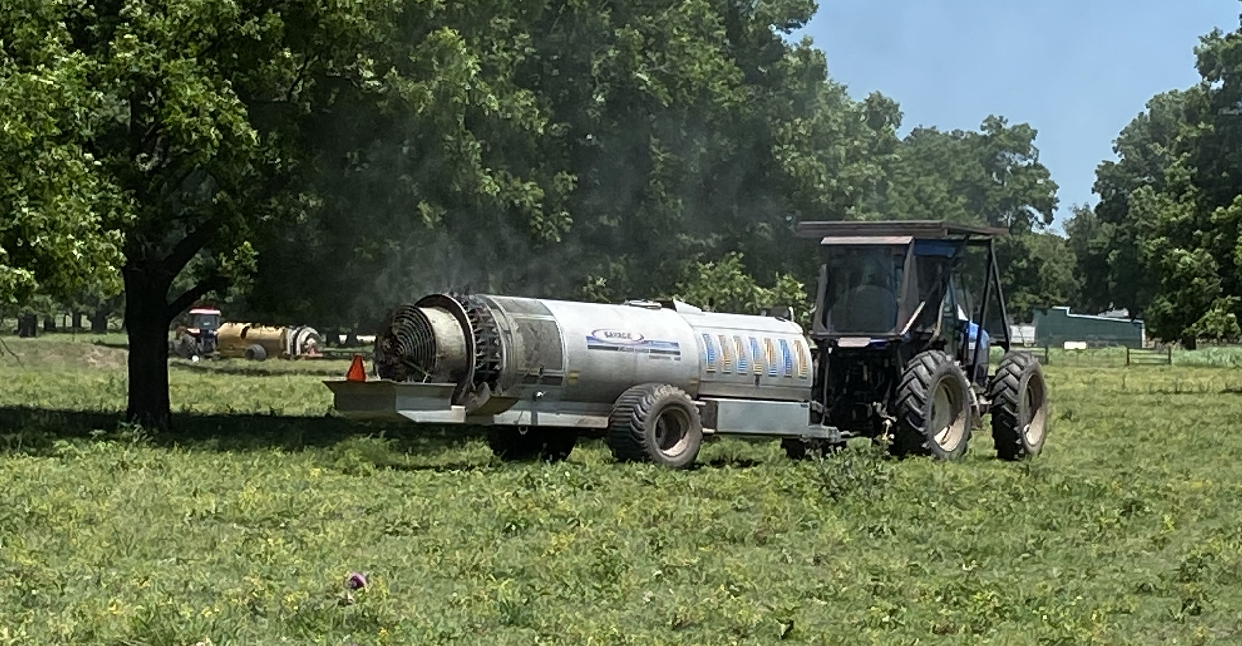 Tanker truck spraying pesticide in a pecan orchard.