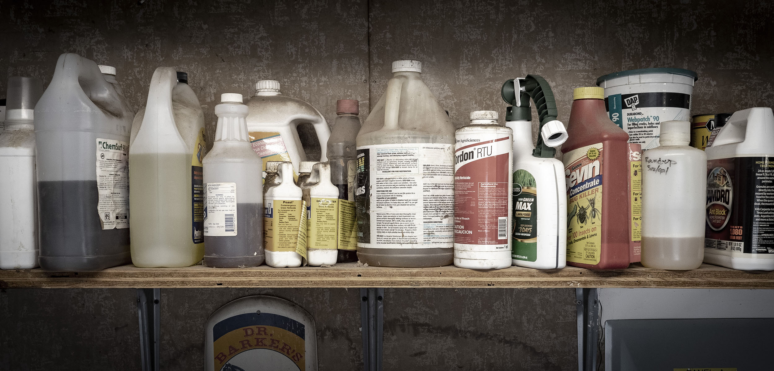 Dusty chemical containers on a shelf.