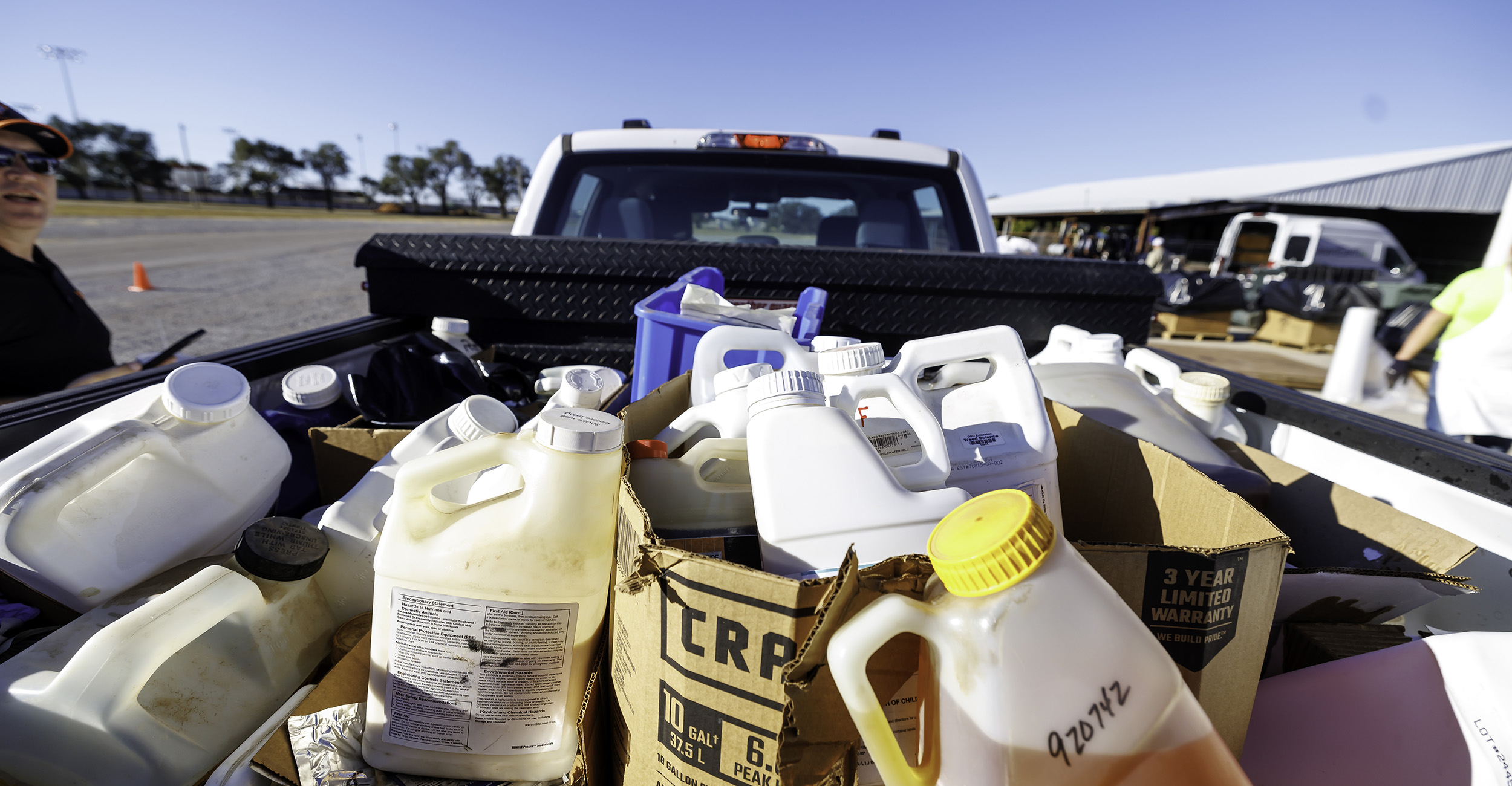 A truck bed is filled with large plastic containers of unwanted pesticides.