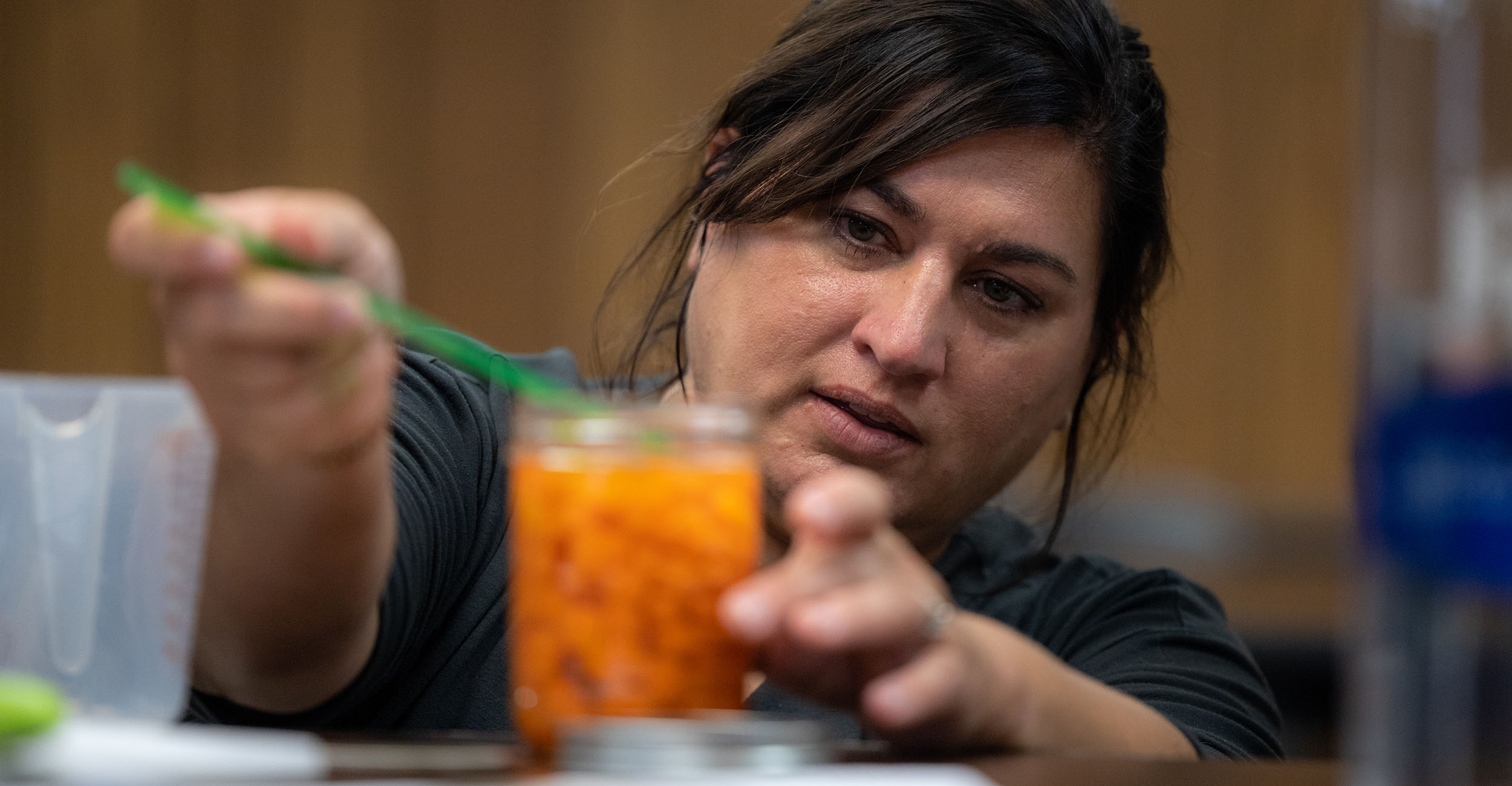 Woman preparing a jar of carrots for canning.
