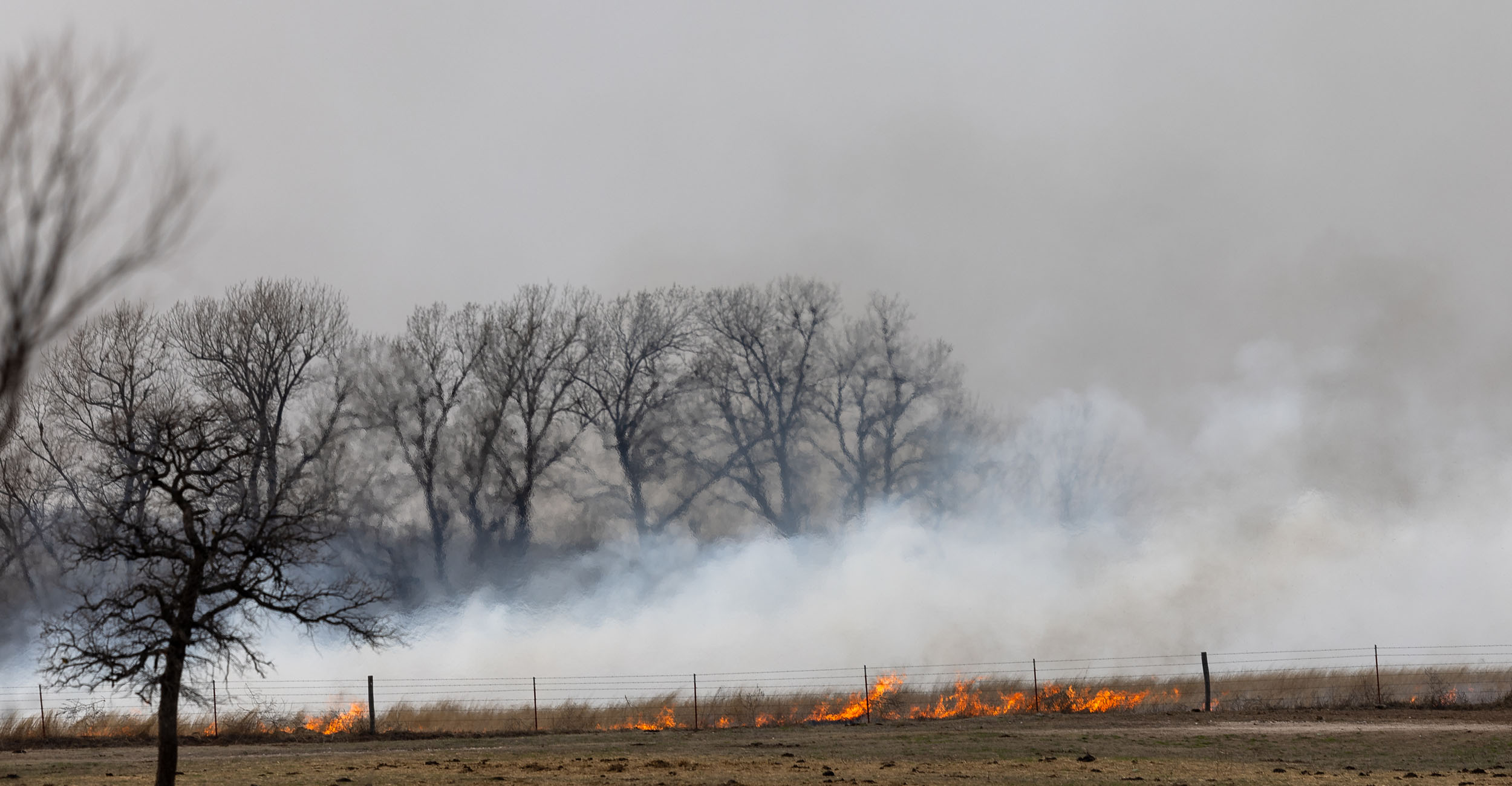 Rural field on fire with a lot of smoke.