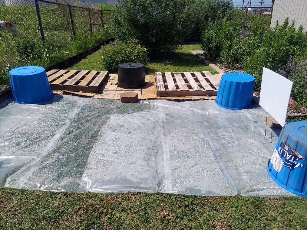 Clear plastic on grass with plastic mineral tubs holding it down. Clear plastic on grass with plastic mineral tubs holding it down.