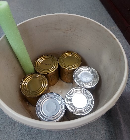 Recycled cafeteria size cans placed in the bottom of a tub.