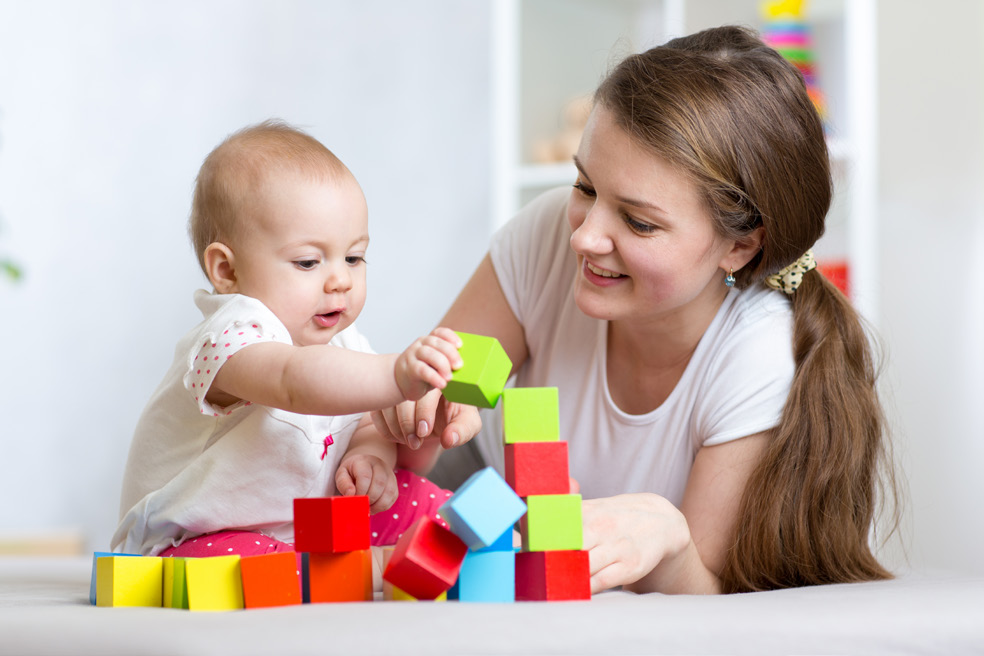 A mother playing with block toys with her baby.