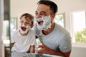 Father and son with shaving foam on their faces.