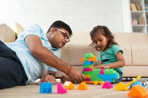 A father playing building blocks with his daughter.
