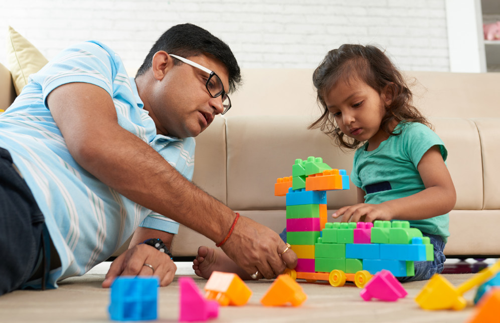 A father playing legos with his daughter on the floor.
