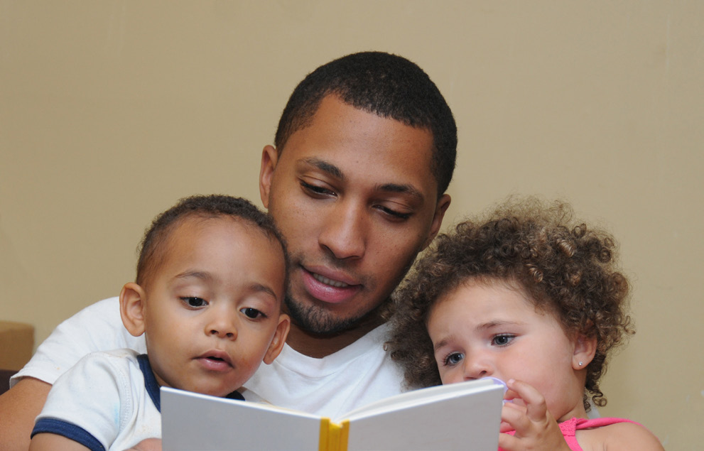 A father reading a book to his two children.