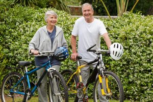 An older man and woman standing beside bikes