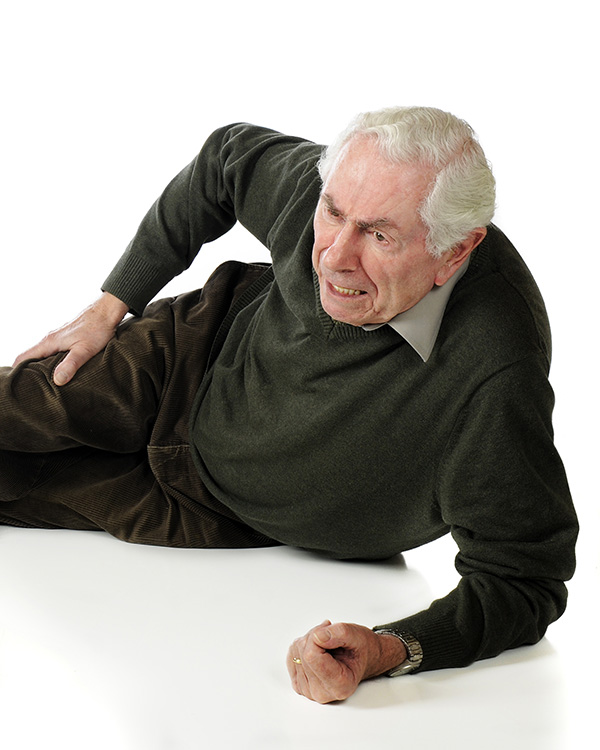 Old man laying on the ground holding his upper thigh with a look of panic.