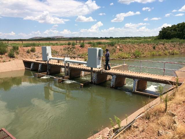 A person is standing by a power box on the platform of the irrigation canal.