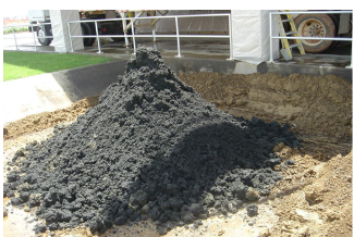 Large pile of biosolids in a dirt pit.