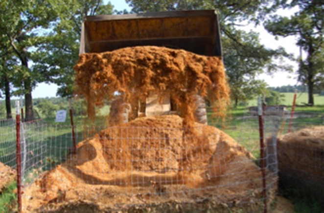 A front end loader turning the compost pile to introduce new oxygen.