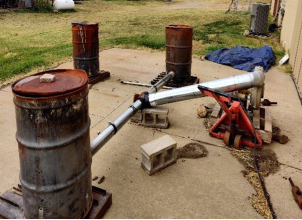 Biochar production on two double barrel system or single barrel in background.