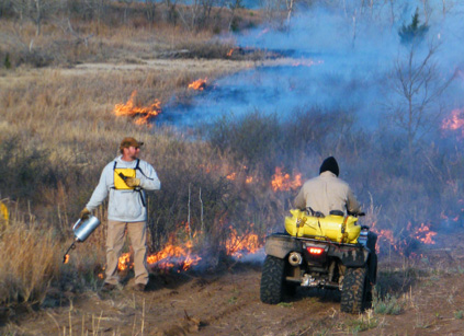 Two men using radios whilst putting out a fire.