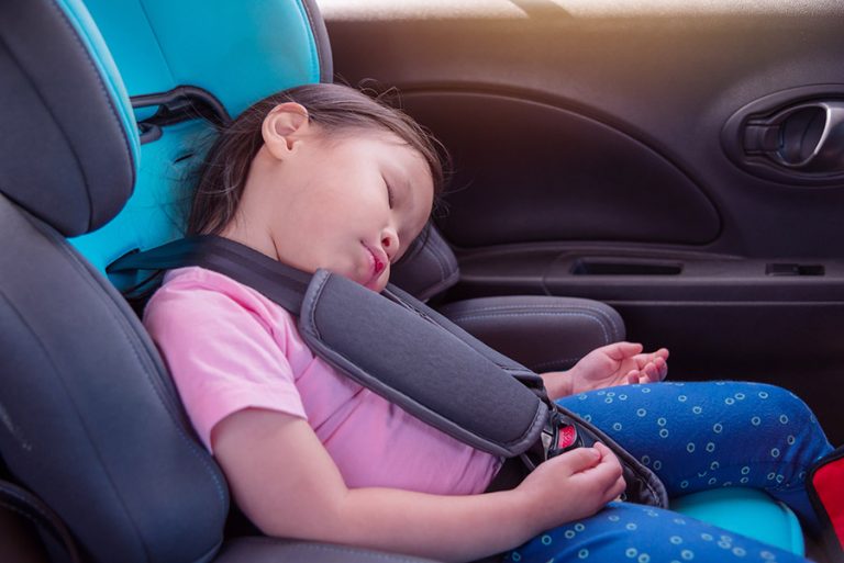 Little girl asleep in a car seat.