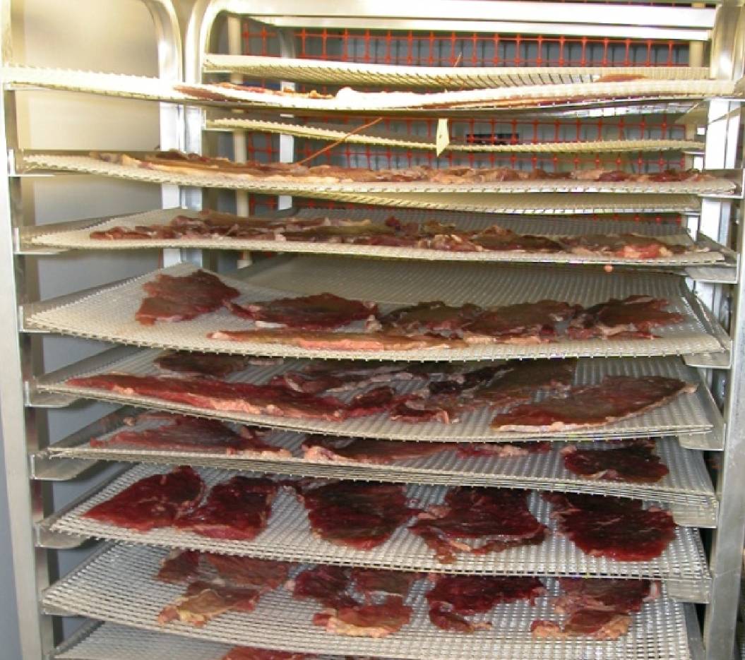 Beef jerky slices on horizontal racks in a dehydrator.