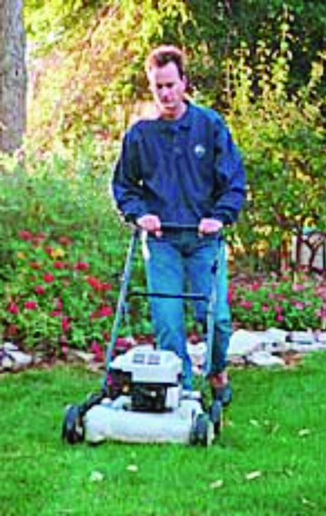 A man push mowing a yard.