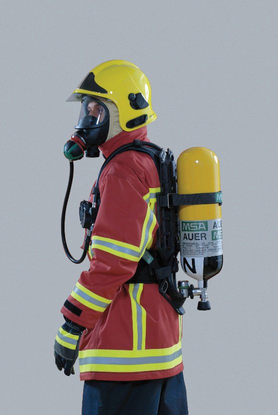 A person wearing an orange reflective jacket with a yellow helmet and full-face gas mask attached to a bottle. A person wearing an orange reflective jacket with a yellow helmet and full-face gas mask attached to a bottle.