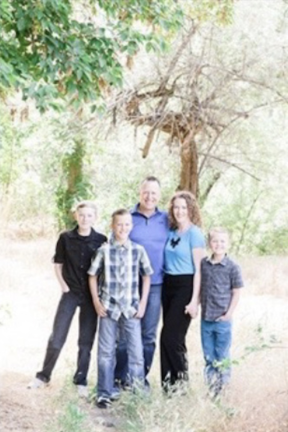 A family wearing blue under a tree, posing for a photo to demonstrate overexposed exposure.