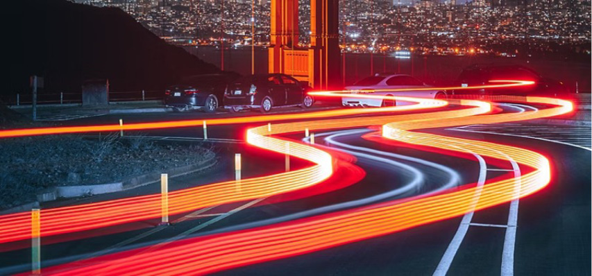 Three cars on a race track with bright neon orange lights outlining the track.