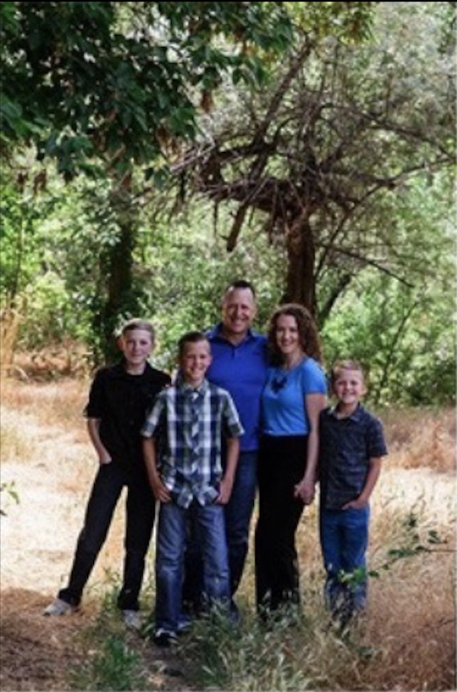A family wearing blue under a tree, posing for a photo to demonstrate underexposed exposure.