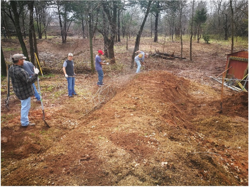 Figure 13 Sustainable Landscapes HLA-6478 A group of 4 people finishing a hügelkultur mound by adding topsoil over layered organic material to create a raised planting bed.