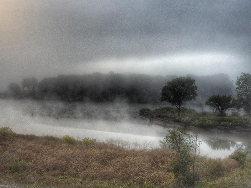 Fog rising over a small pond with trees in the background. Fog rising over a small pond with trees in the background.