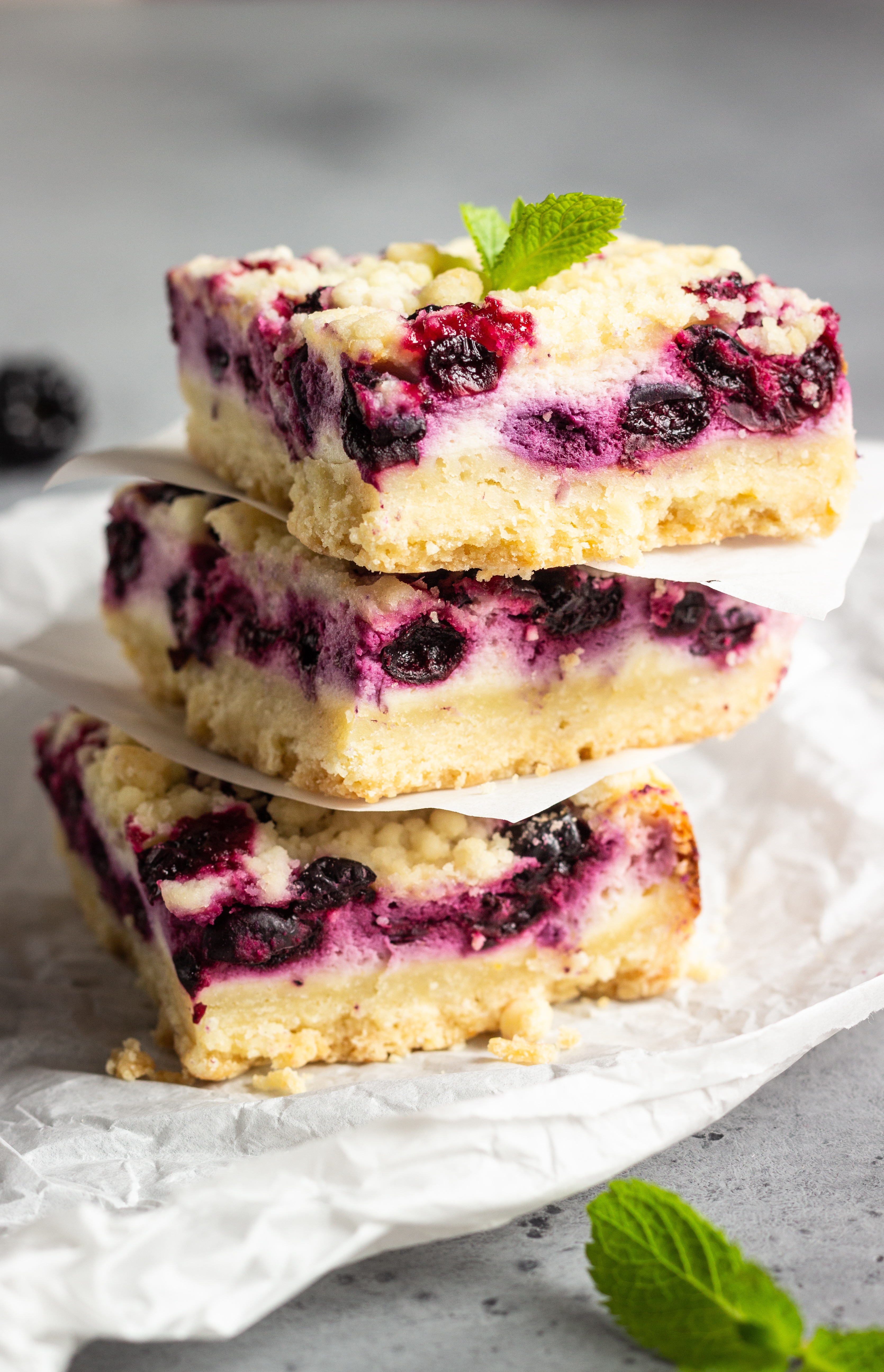 A blueberry cheesecake bar cut into three slices sitting on top of one another.