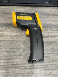 A black and yellow infrared thermometer sitting on a table.