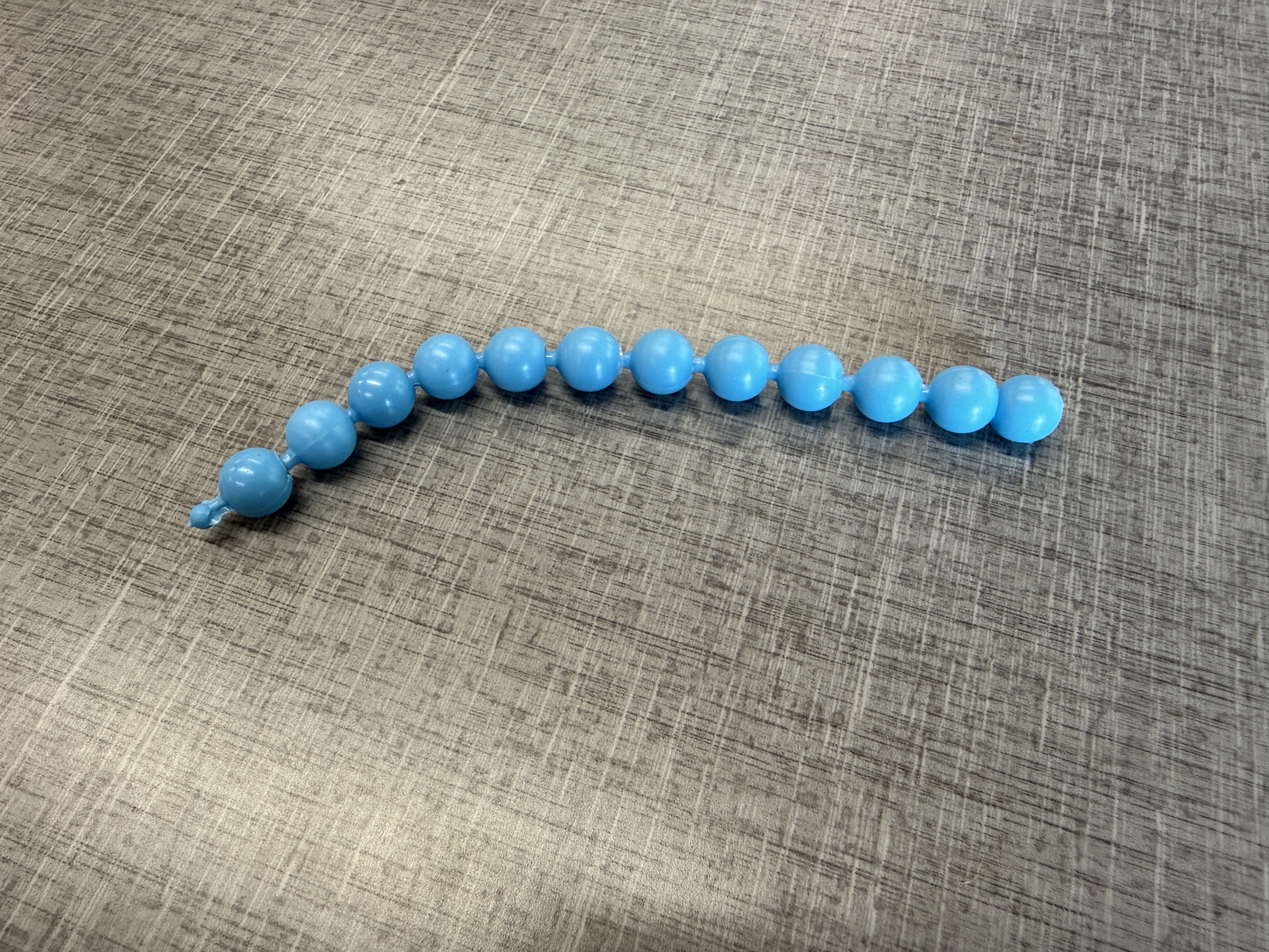 Blue pop beads in a line sitting on a counter.